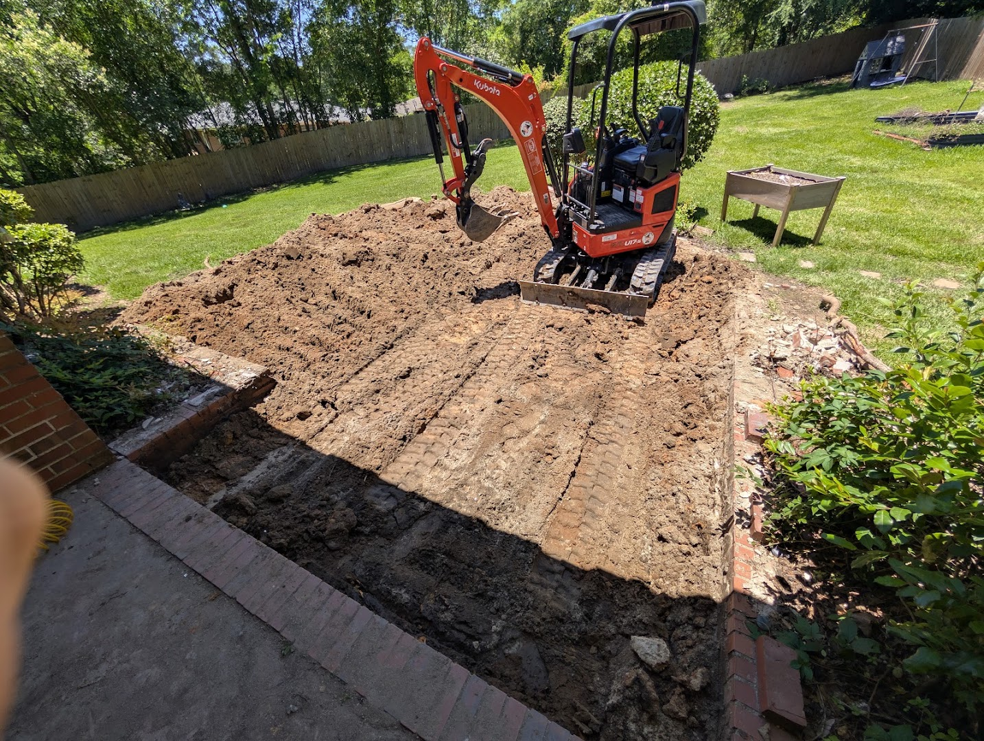 Compact excavator grading a residential backyard work area