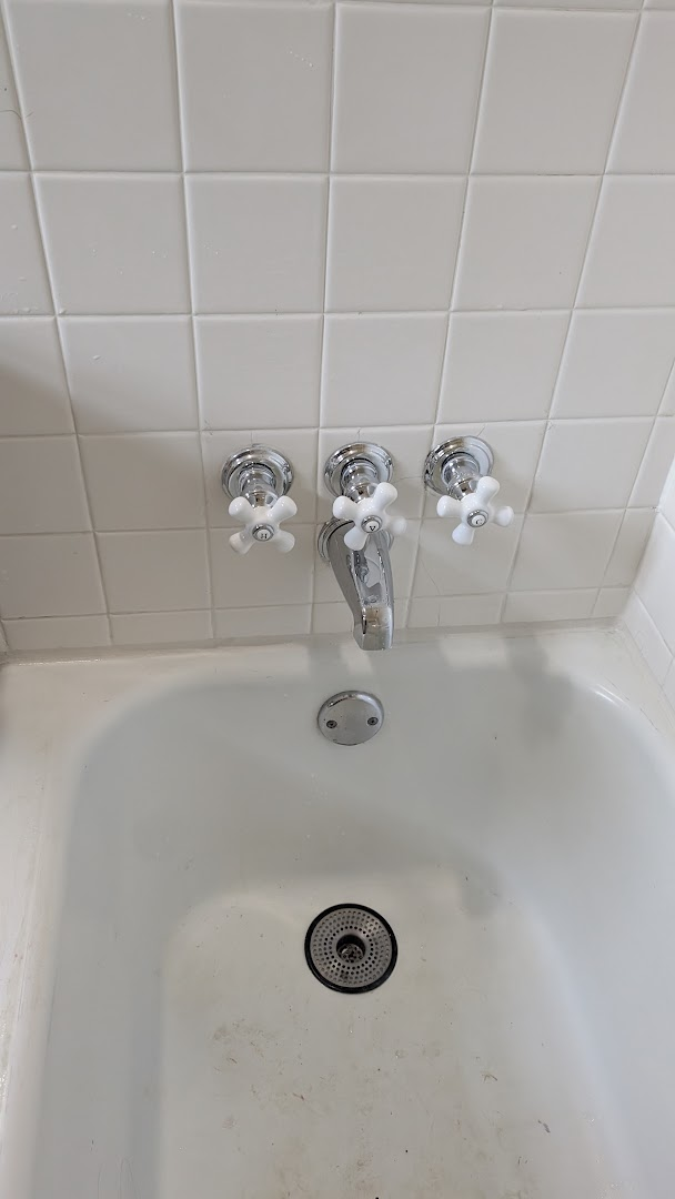 Bathtub wall with three new chrome and white shower handles after repair